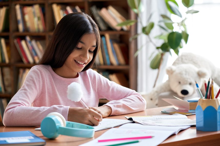 Young girl studying at home sitting at a desk.