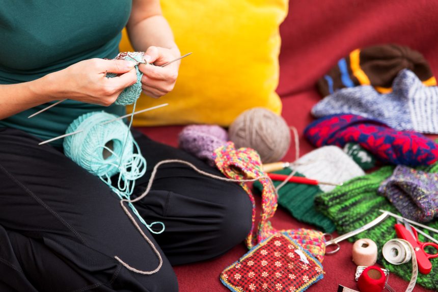 Woman knitting on her couch.