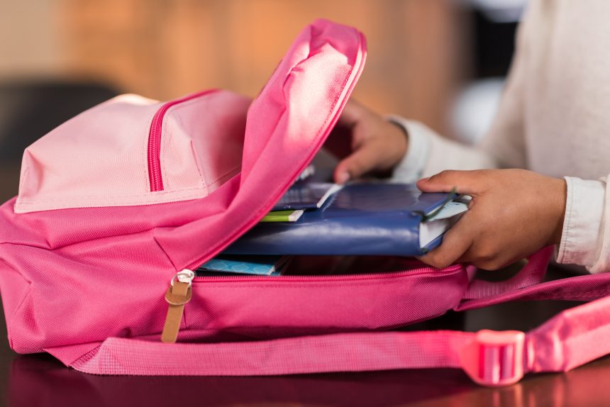 A girl packing her school backpack.