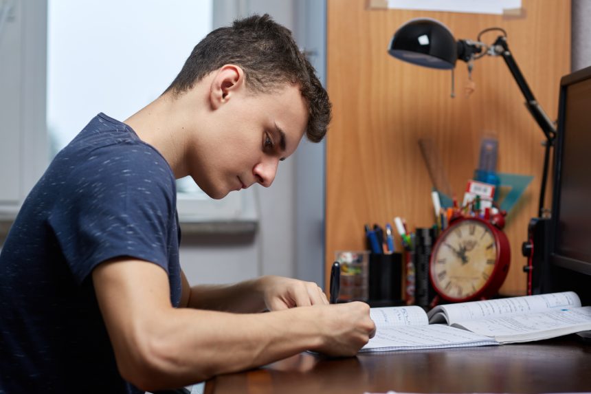 A male sixth form student independently studying at home.