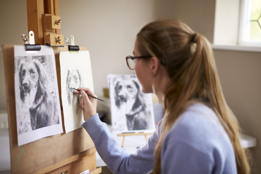 A teenage girl sitting at an easel and drawing for her EPQ.