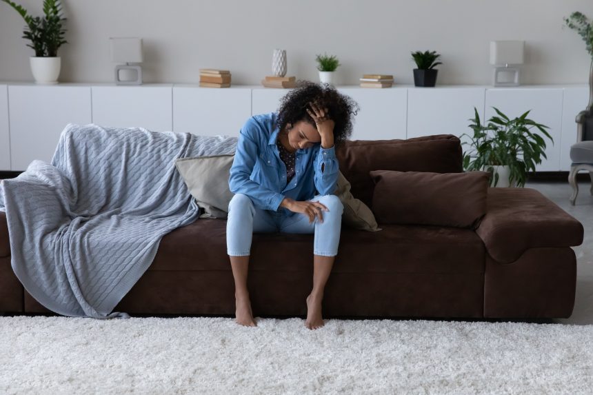 A stressed and anxious mother sitting on her sofa.