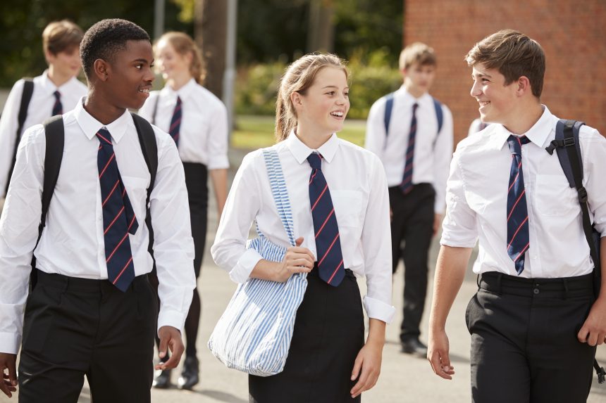 A group of school students walking across the school yard.