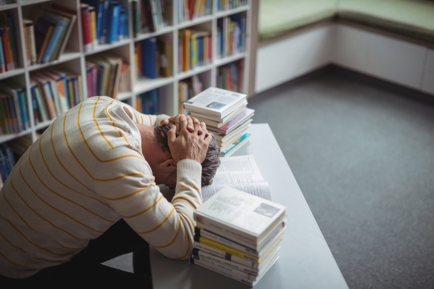 A burnt out school teacher with his head on the desk.