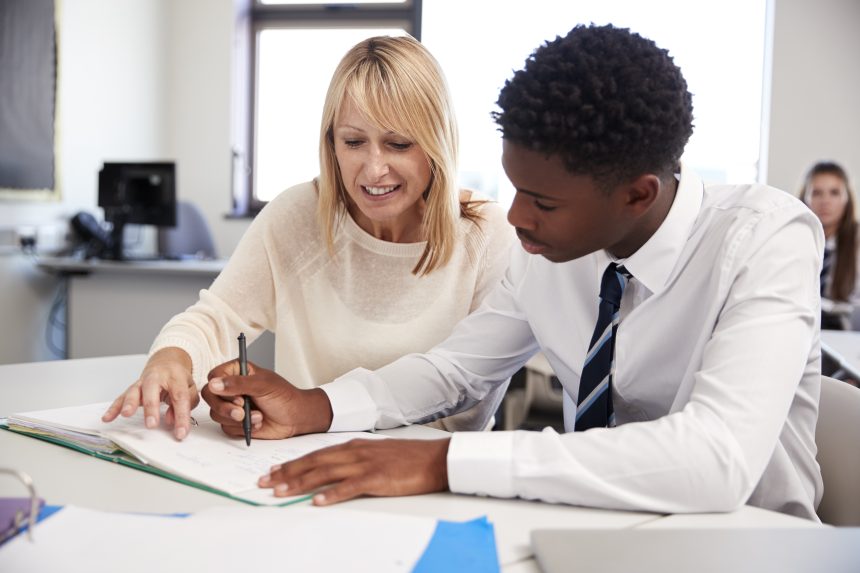 Secondary school teacher providing one-on-one support to a pupil.