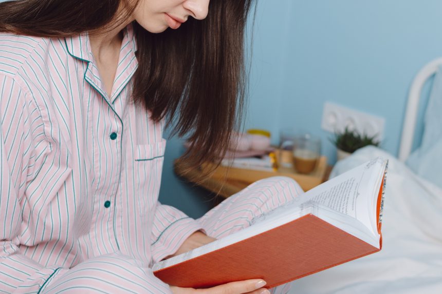 Teenager reading a book in bed.