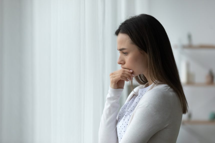 A woman looking out of the window and self-reflecting.