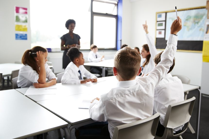 Secondary school students raising their hands to answer a question.