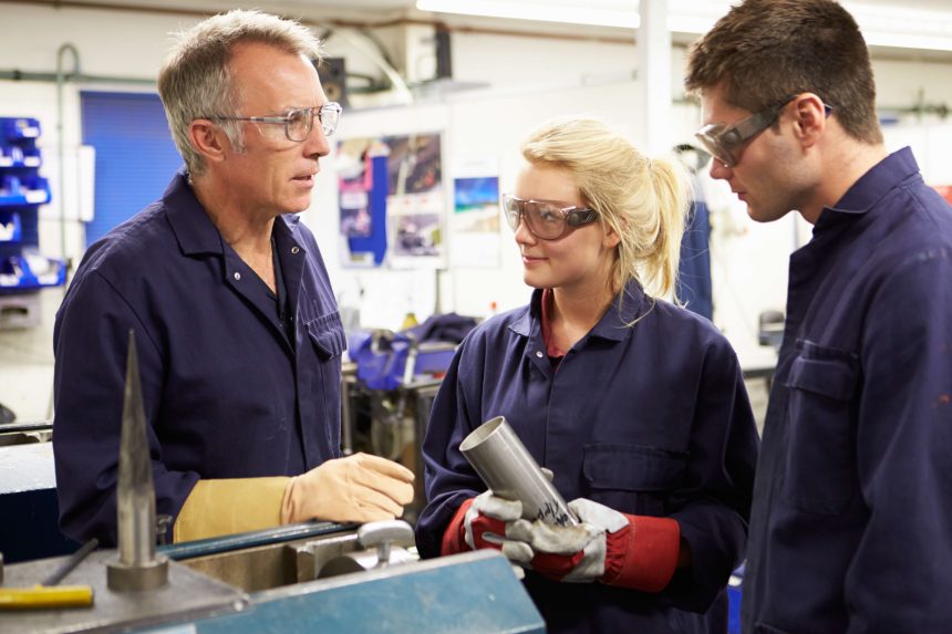 A female apprentice working with two male engineers. In STEM, the gender gap remains significant.