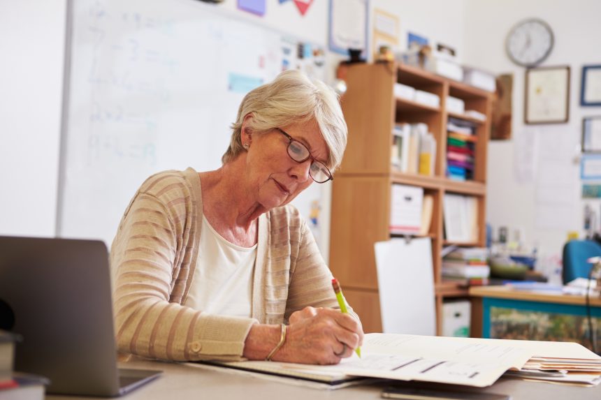 Female teacher marking worksheets.