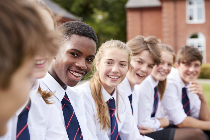 Group of smiling teenage students outside school buildings