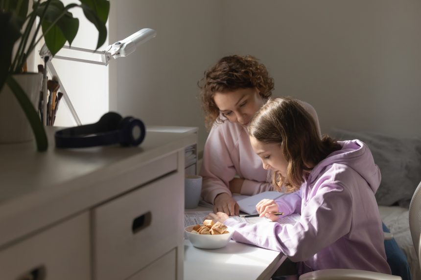 A mother offering homework guidance to her daughter.