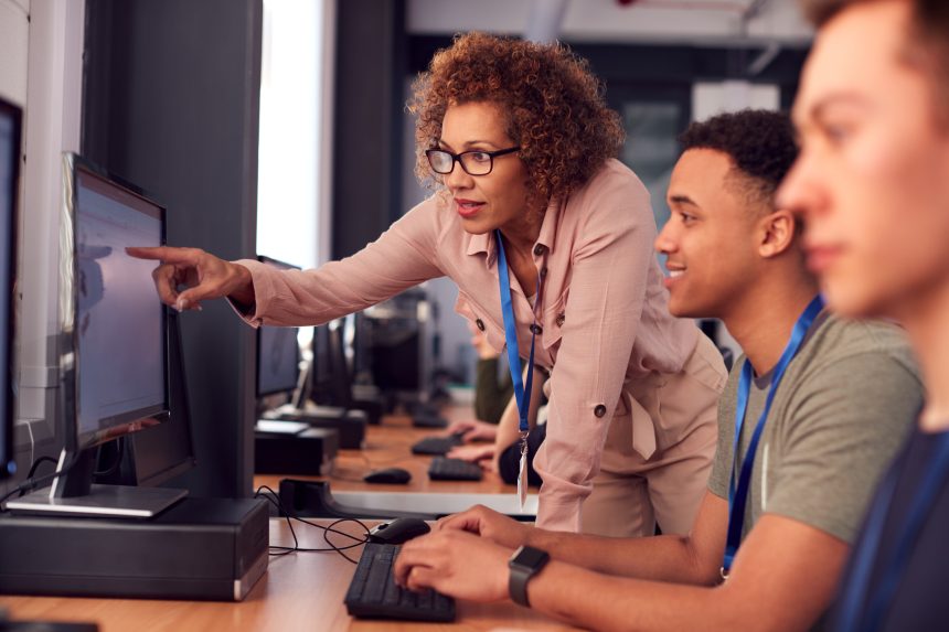 Female teacher helping sixth form students with university research.