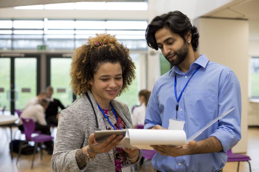 A male and female teacher discussing a piece of work.