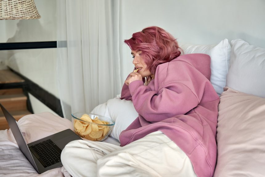 A teenage girl relaxing in bed whilst watching Netflix.