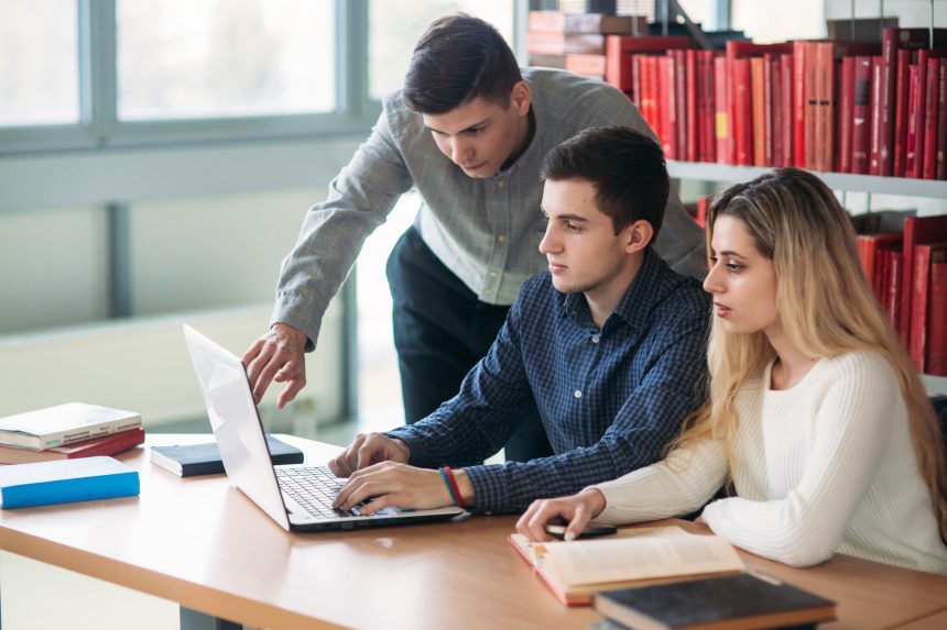 Three university students working on a group project in the library.