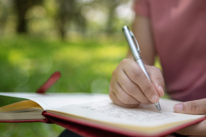 Young girl writing a poem in the park.