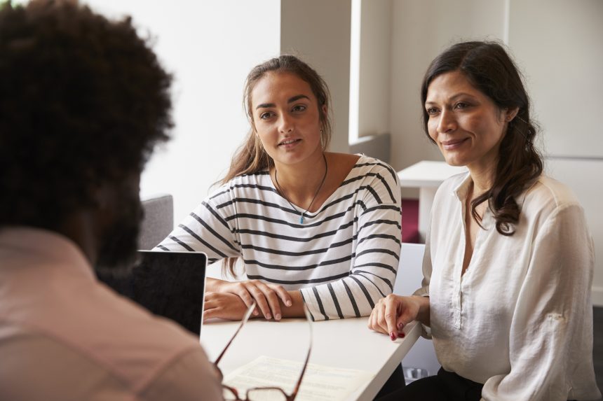 Mother and daughter meeting male teacher at parents' evening.