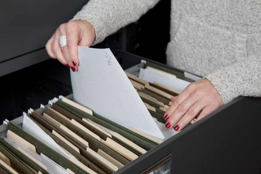 Teacher organising worksheets in filing cabinet.