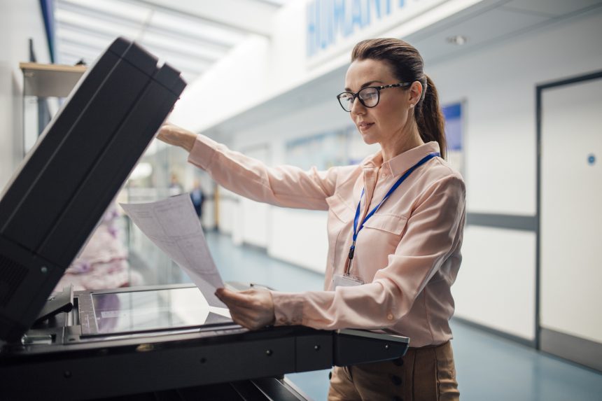 Teacher making copies of her resources using a photocopier.