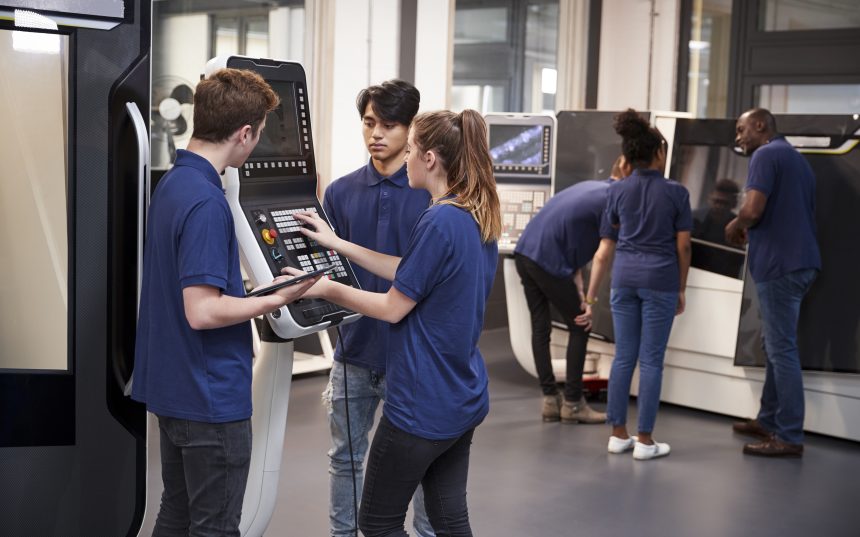 Engineer showing apprentices how to use a machine.