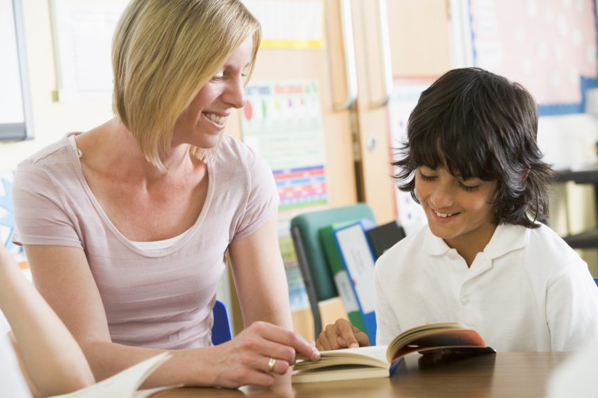 Female teacher reading one-on-one with a male student during form time.