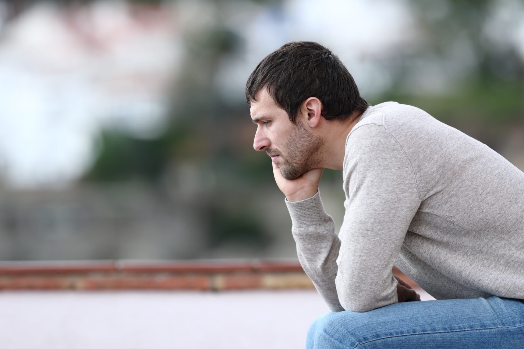 Pensive and burnt out tutor sitting on a bench.