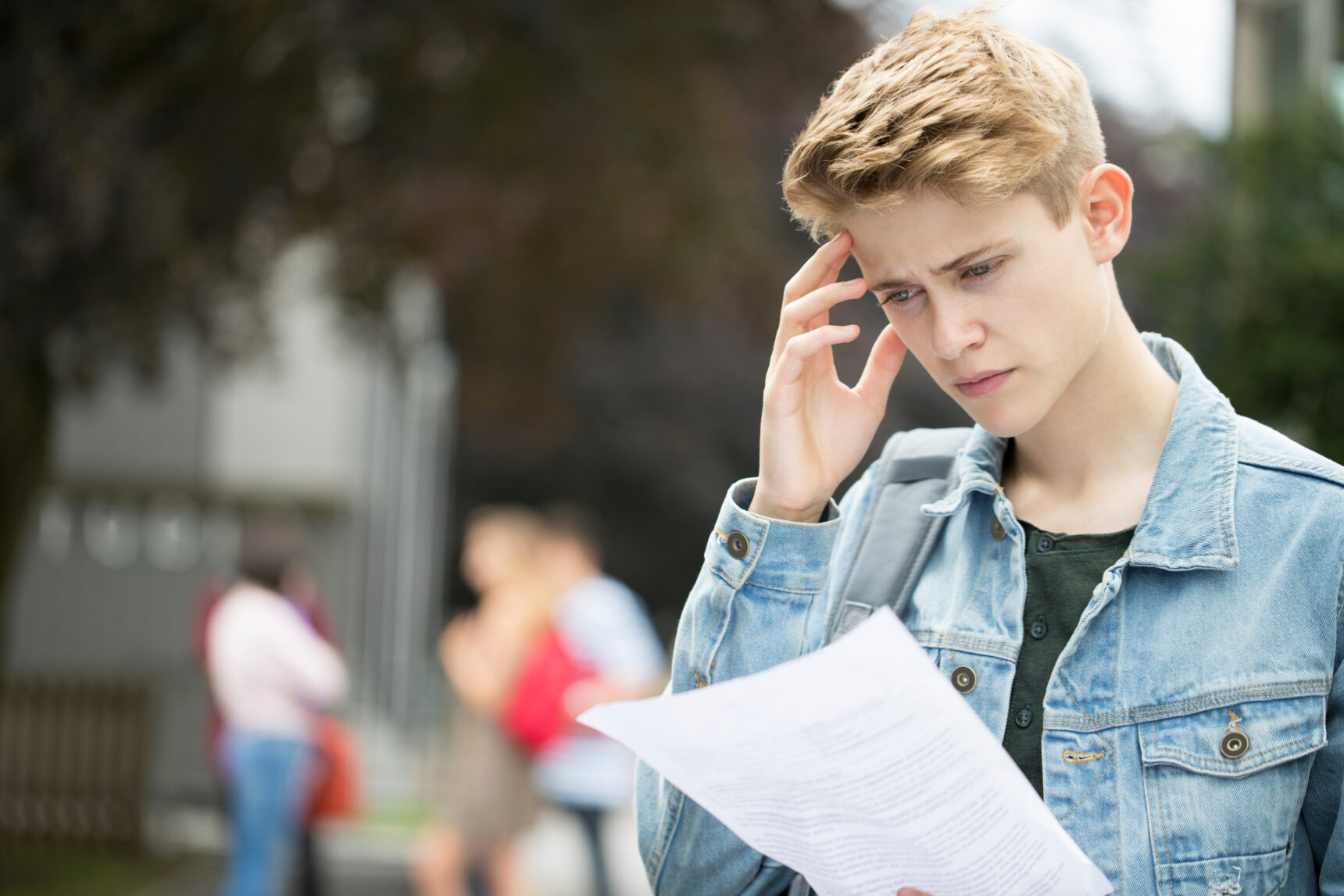 A teenage boy looks worried and disappointed as he looks at his results slip on GCSE Results Day 2025.