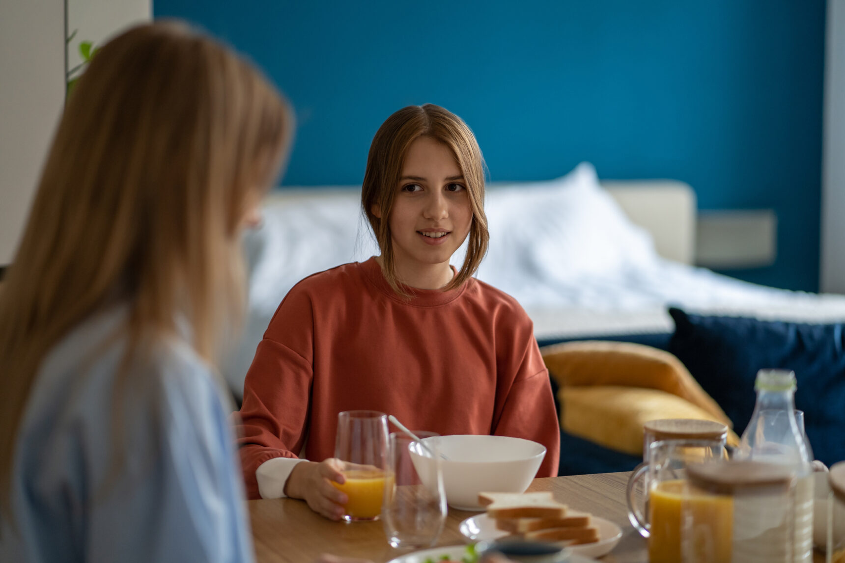 A teenage girl is having breakfast with her mother on GCSE Results Day 2025.
