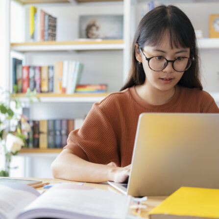 A teenage girl sitting at a desk with her laptop taking part in the online GCSE Geography Paper 3 Exam Technique Course.