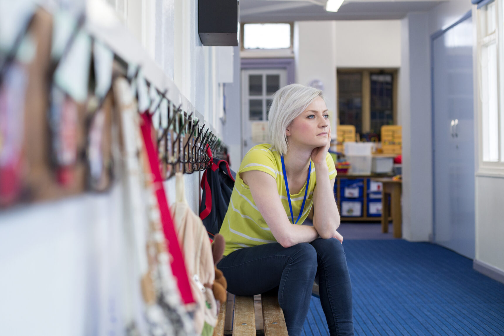 Tired female teacher sat outside classroom.