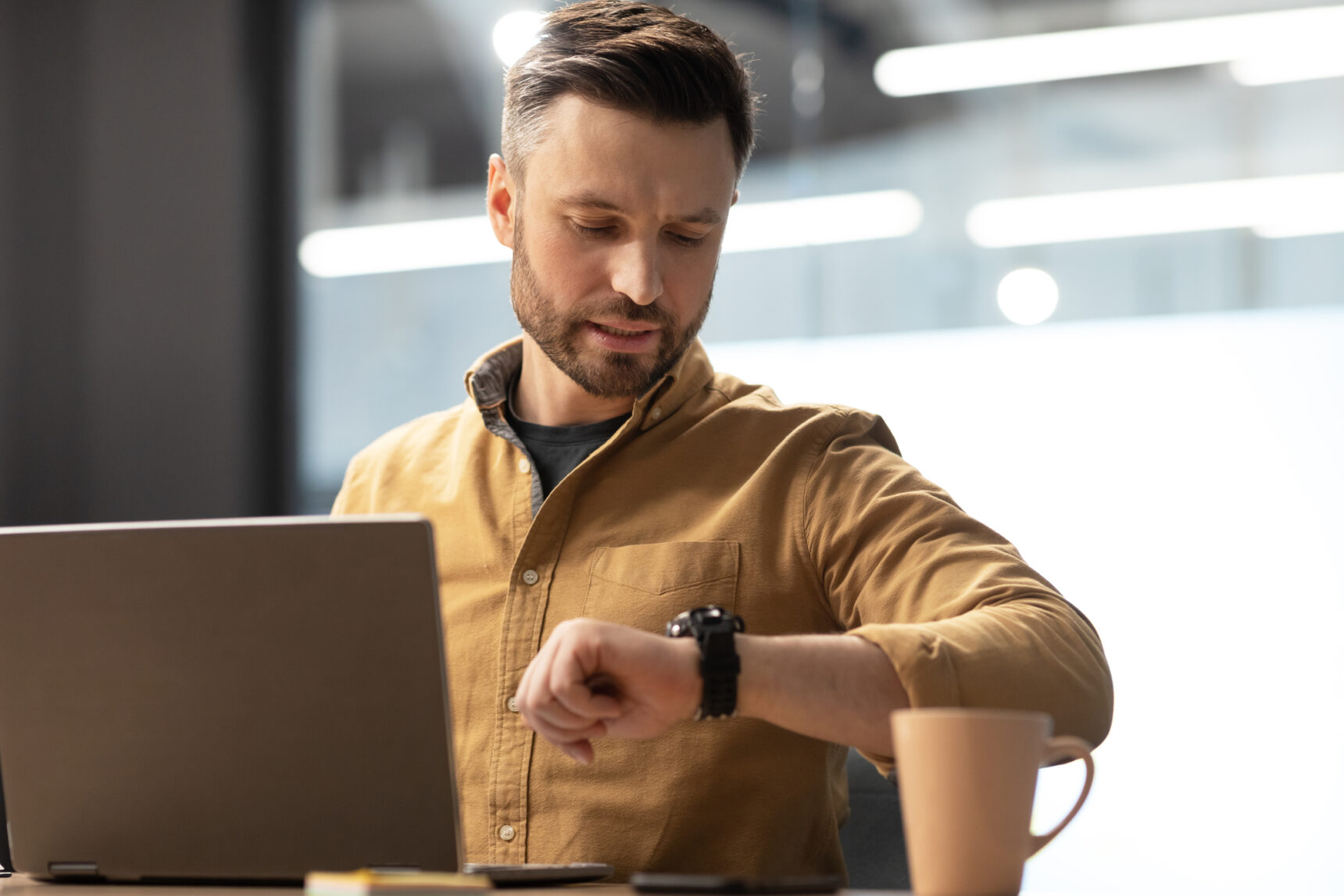 A male online tutor is checking his watch as he waits for a student to show up for a lesson.