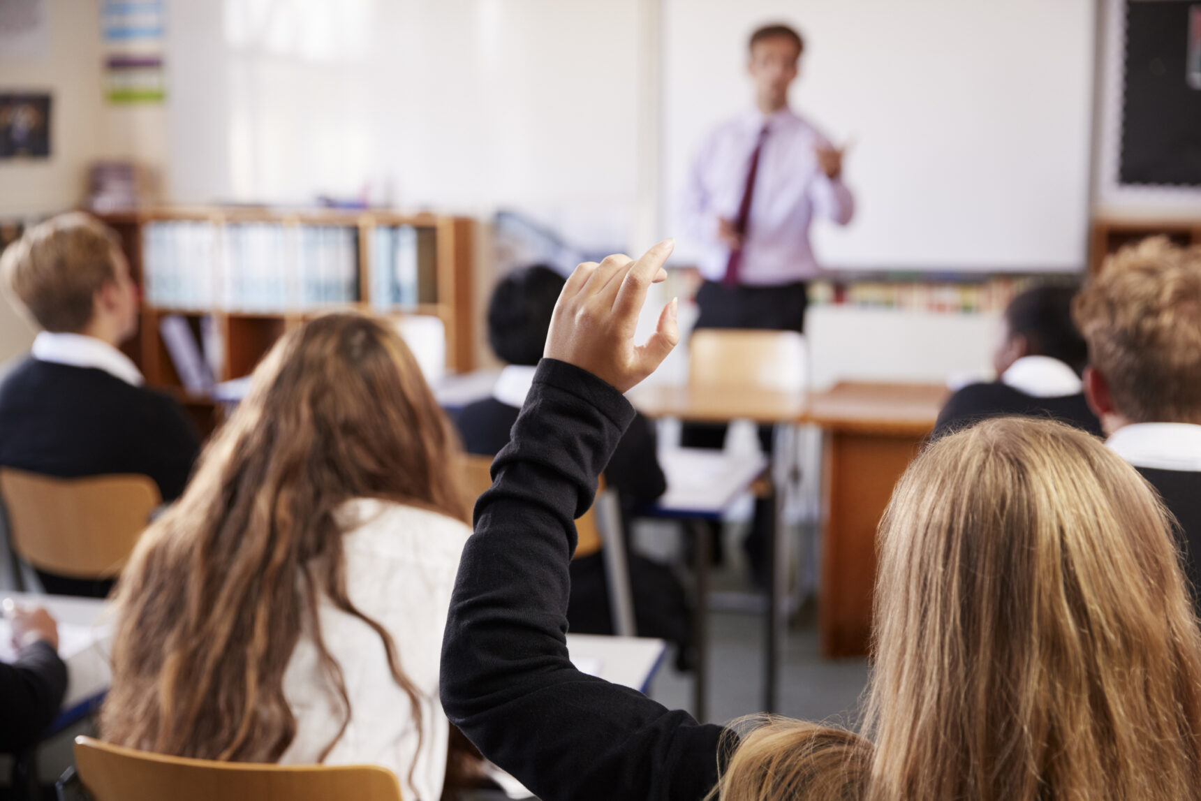 A male teacher is posing a question to a classroom full of students.