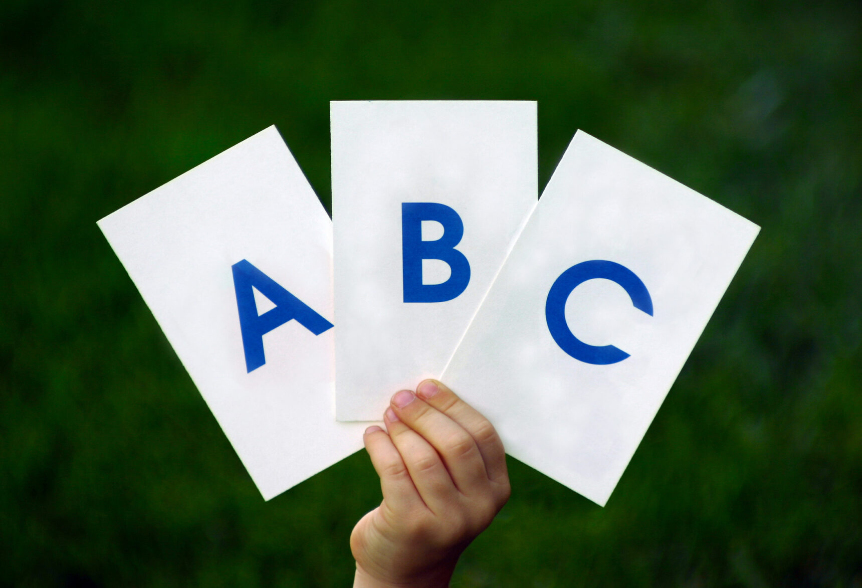 A hand holding up three ABC questioning cue cards.