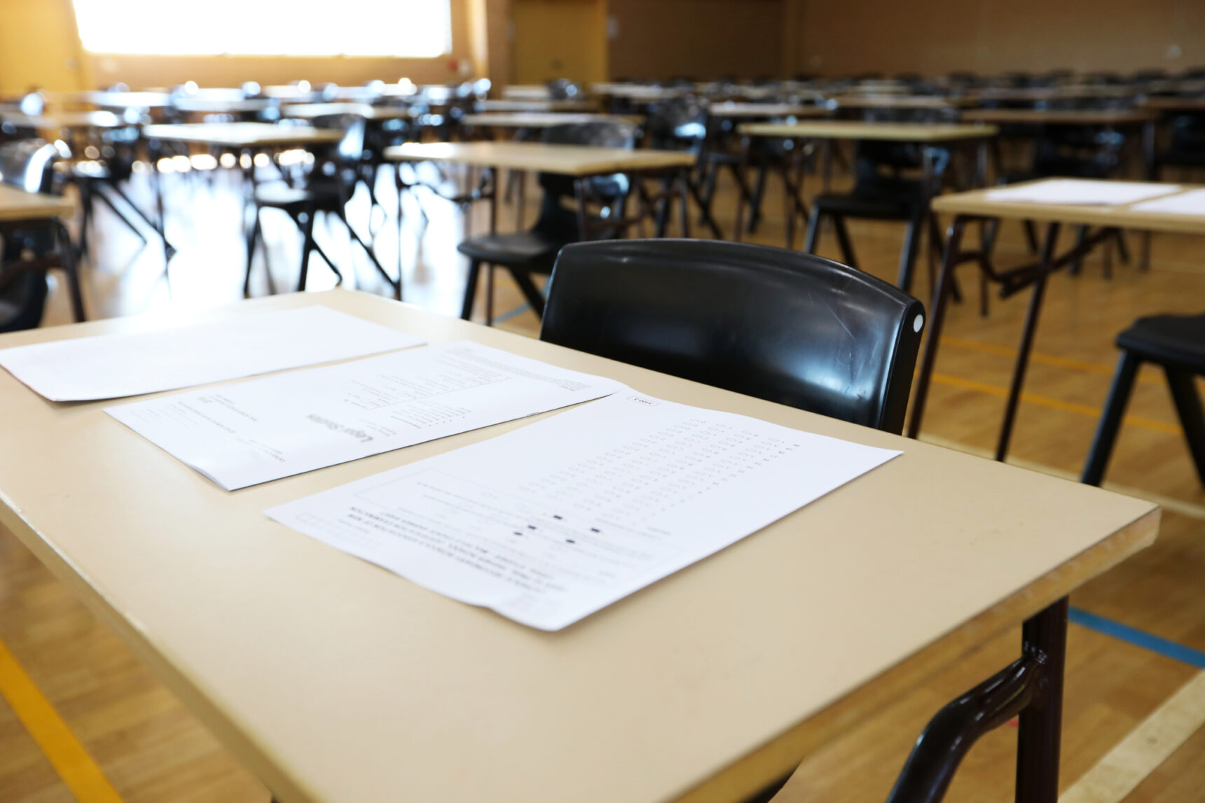 An exam room is laid out ready for an exam with exam papers on the desks.