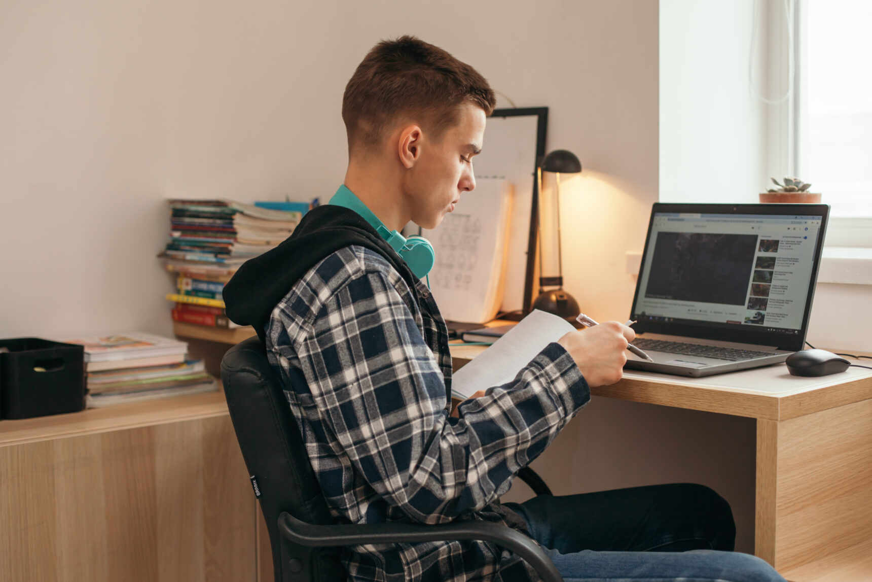 A teenage boy reads at a desk as he studies for exams.