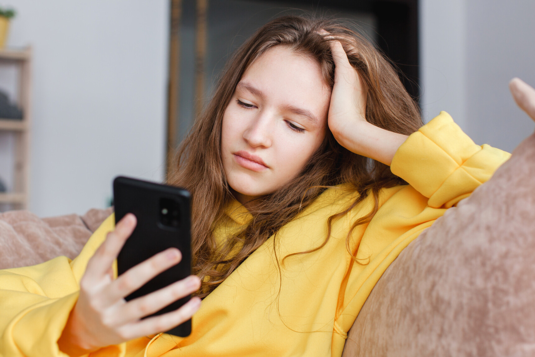 A teenage girl is scrolling on her phone instead of studying for exams.