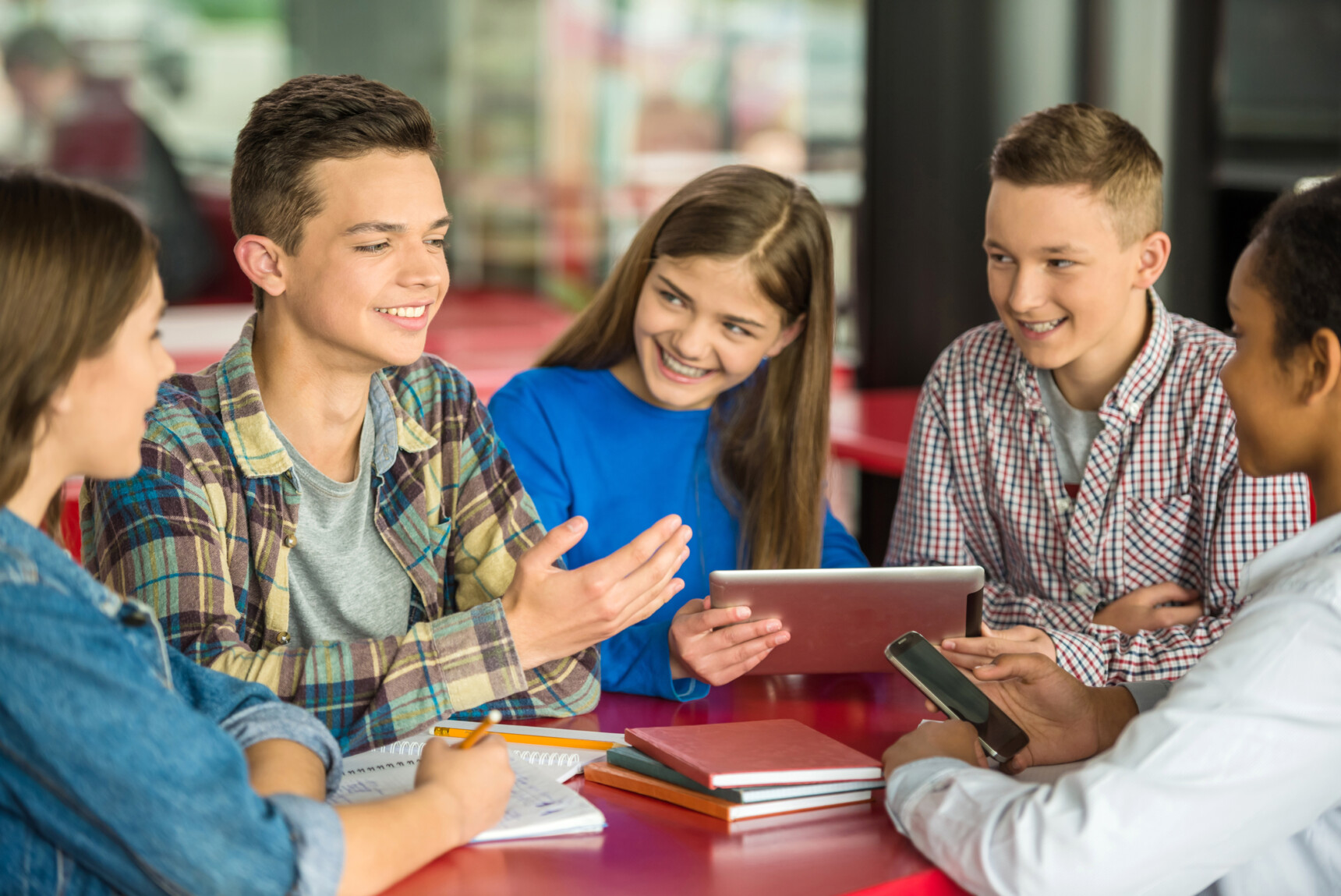 A small group of home edicated teenagers are studying together in a cafe.