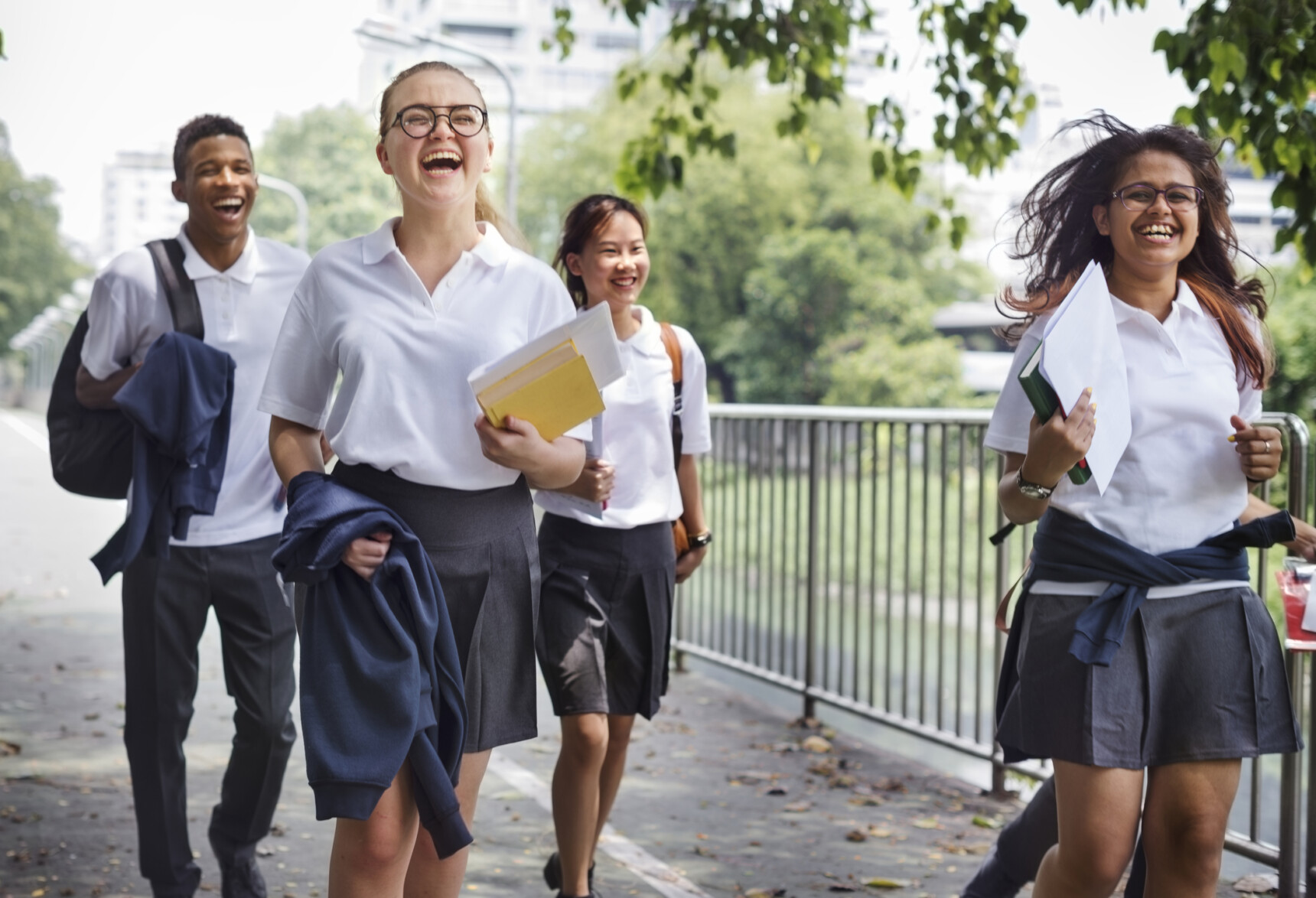 A diverse group of students wearing the same school uniform walk together to school. The students may seem equal.