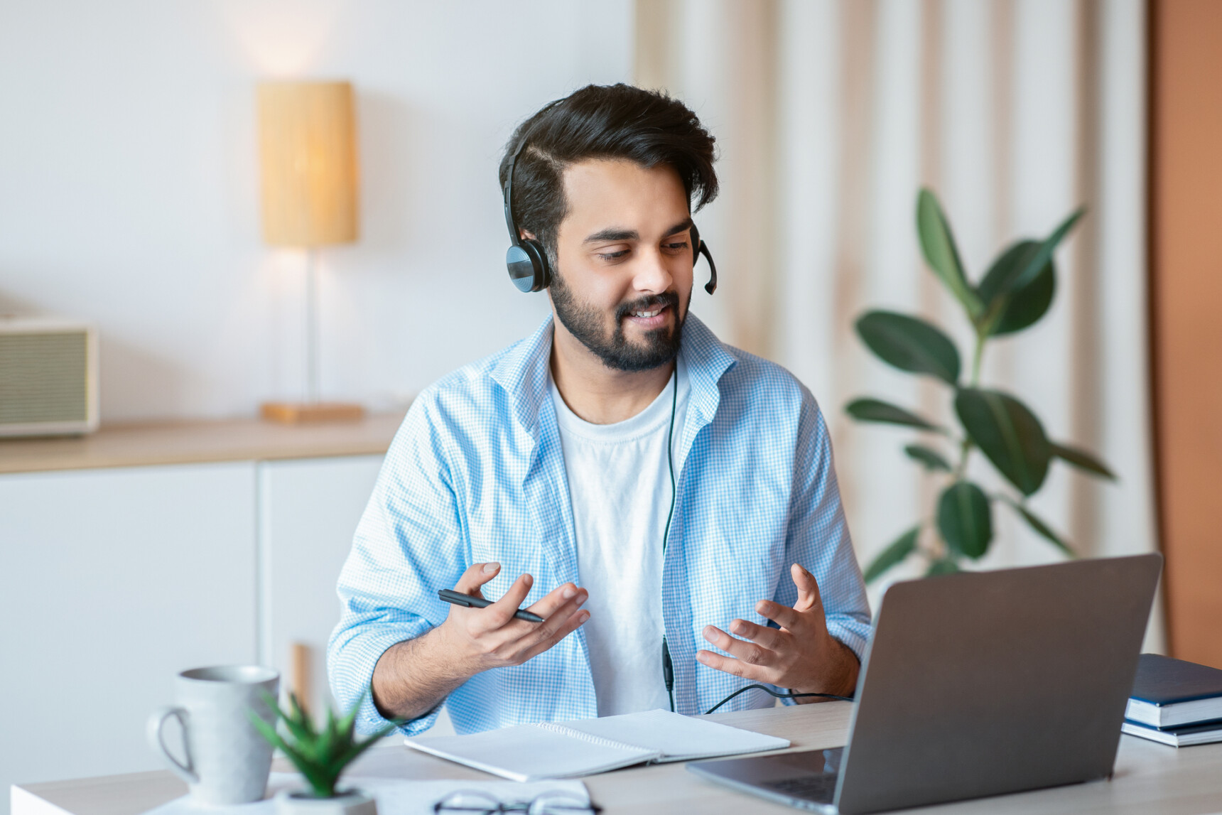 A male online tutor is giving verbal feedback to a student during a tutoring session.