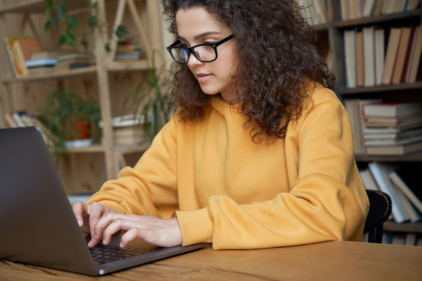 A female home-educate student is comparing exam board specifications on her laptop.