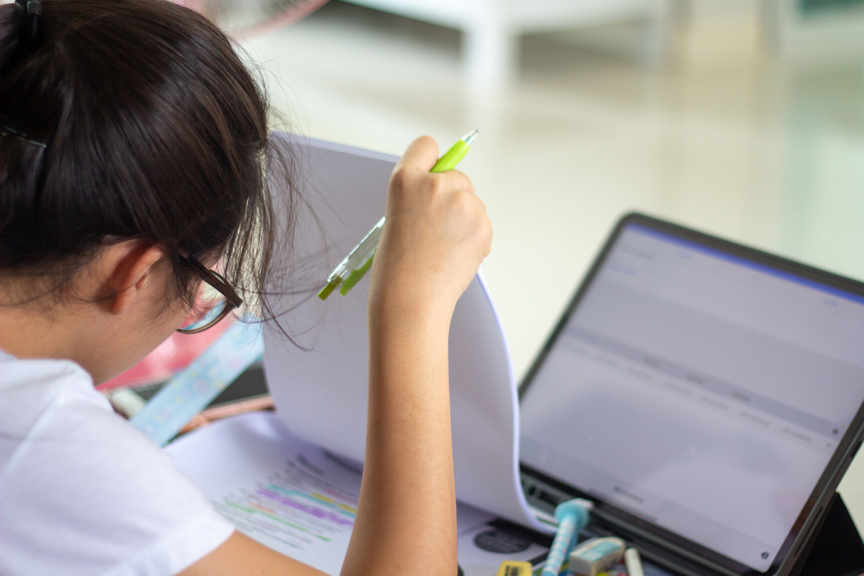 Girl reading notes and using her iPad to complete homework set by her tutor.