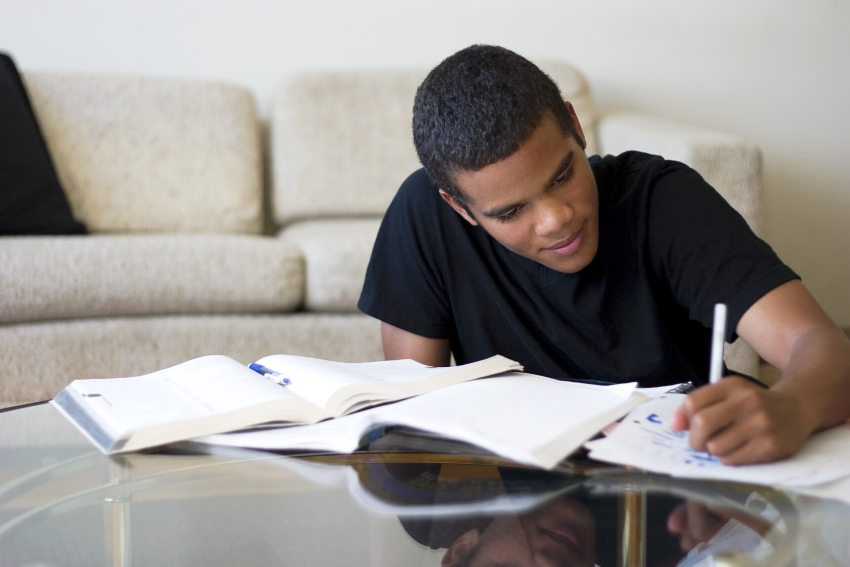 A home-educated teenage boy is writing notes as he studies for a GCSE exam.