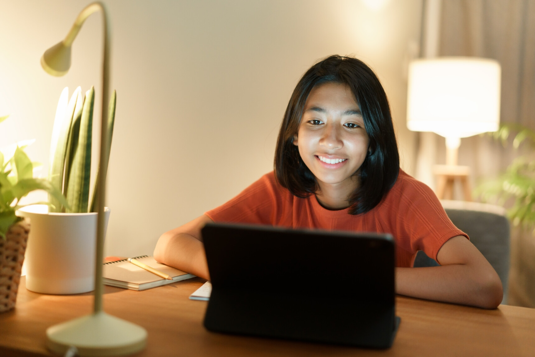 A female home-educated teemager sitting at a desk with a laptop receiving online tuition.