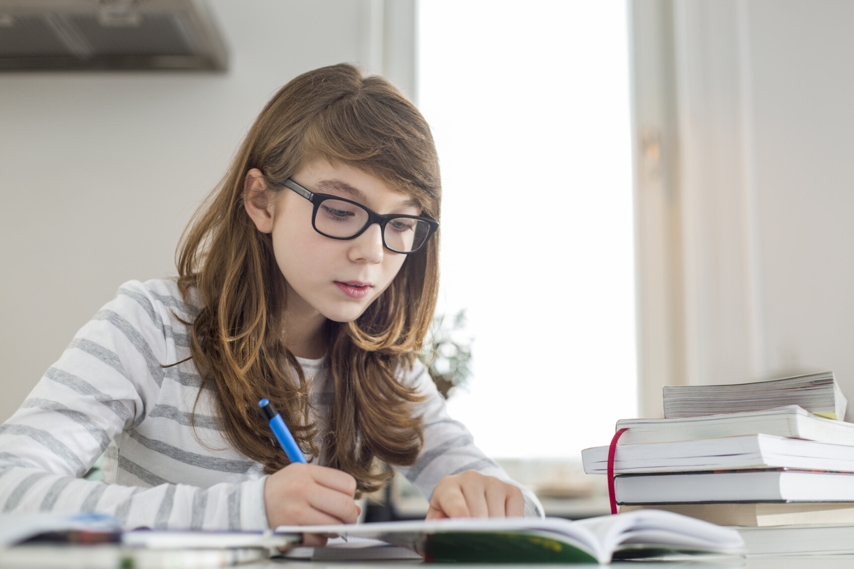 A home-educated teenage girl is taking notes from a textbook as she studies for a GCSE exam.