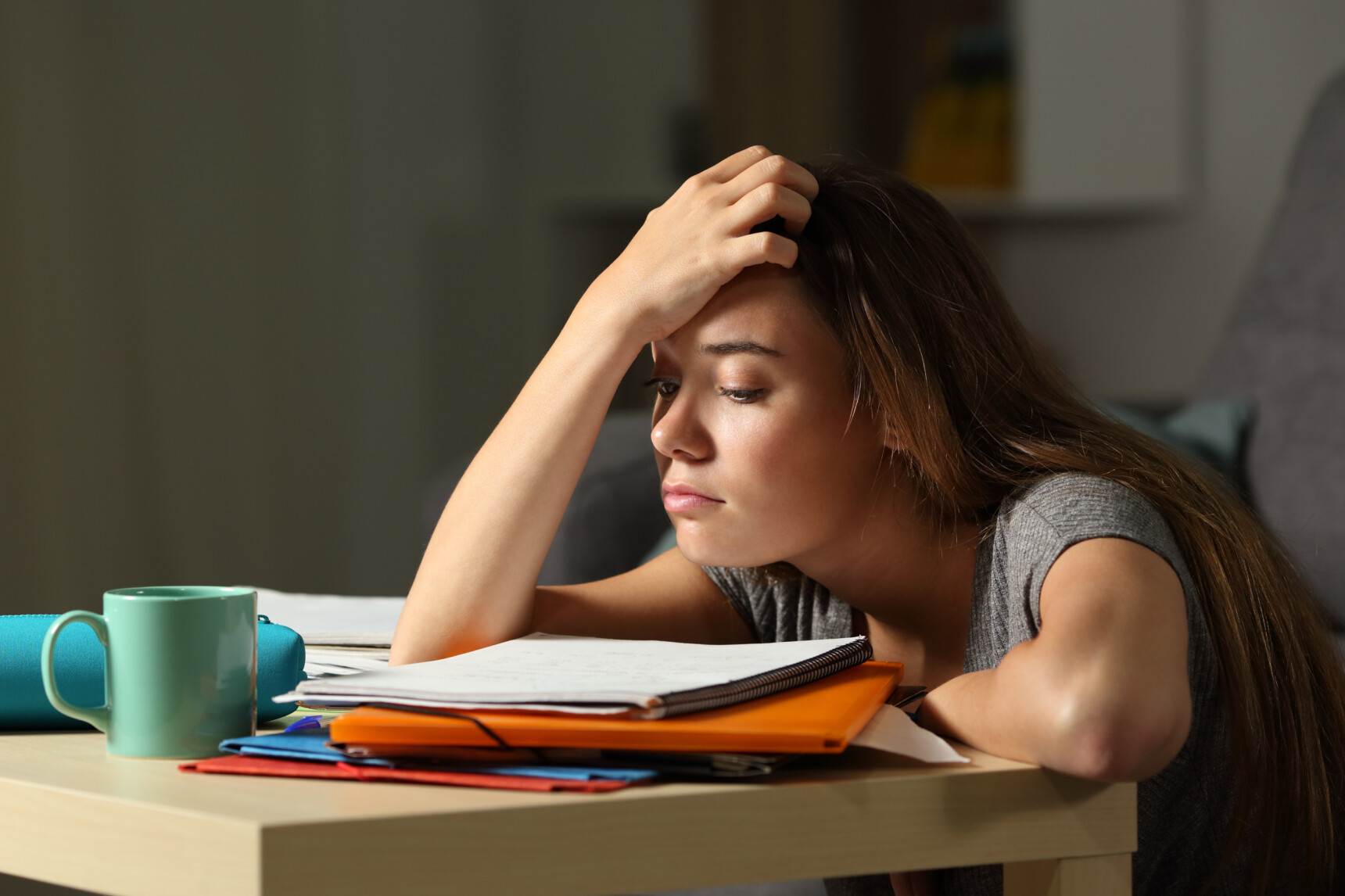 Stressed student looking at study notes and textbooks while deciding how many A Levels to choose and which A Level subjects to study.